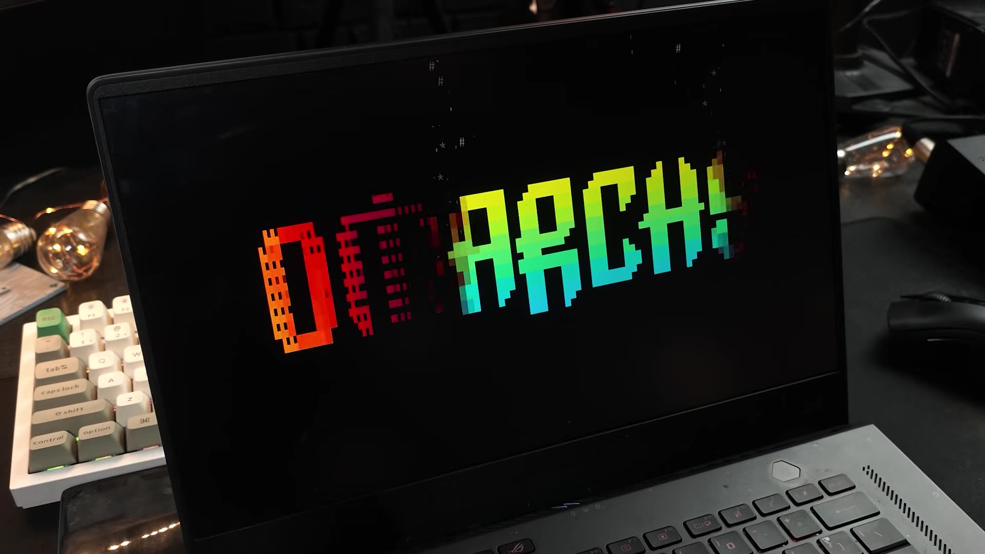 The Omarchy pixel-art boot splash on the laptop